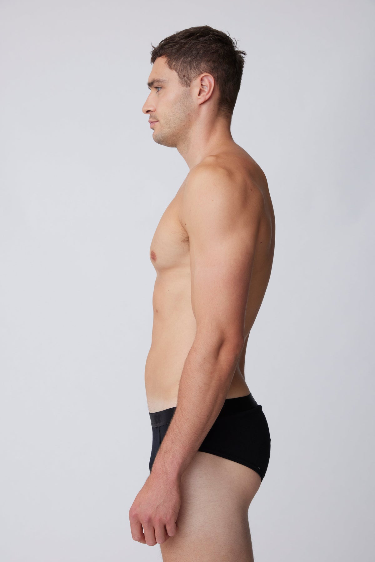 
            White, brunet male wearing only black brief from the side
