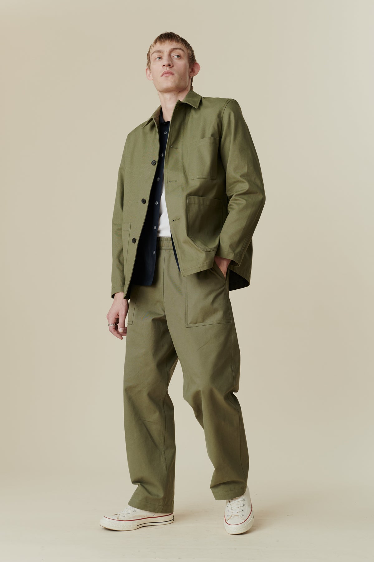 Full body image of white male wearing chore jacket in olive paired with chore jeans in olive