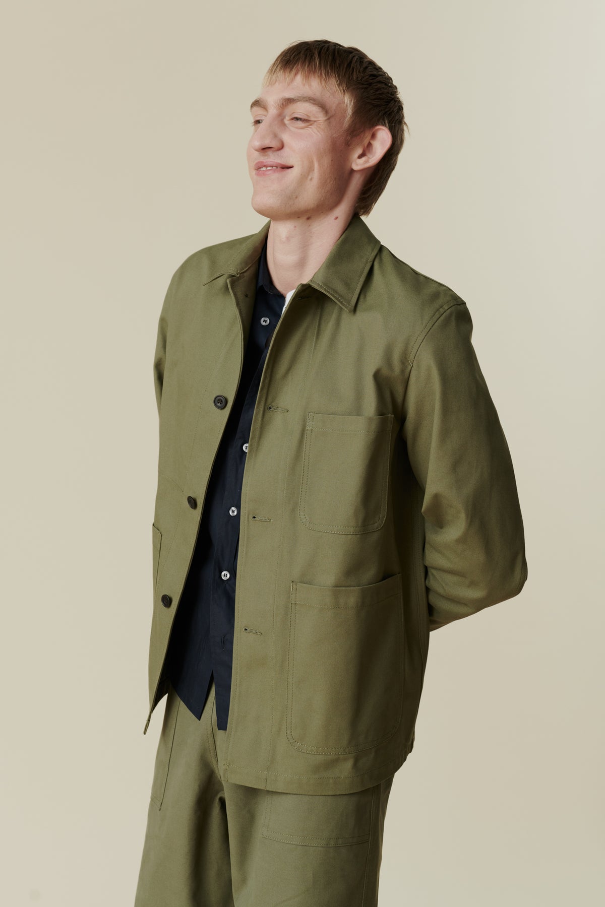 
            Image of white male, waist up wearing men&#39;s chore jacket in olive. Collar, button fastening detail, front pockets 