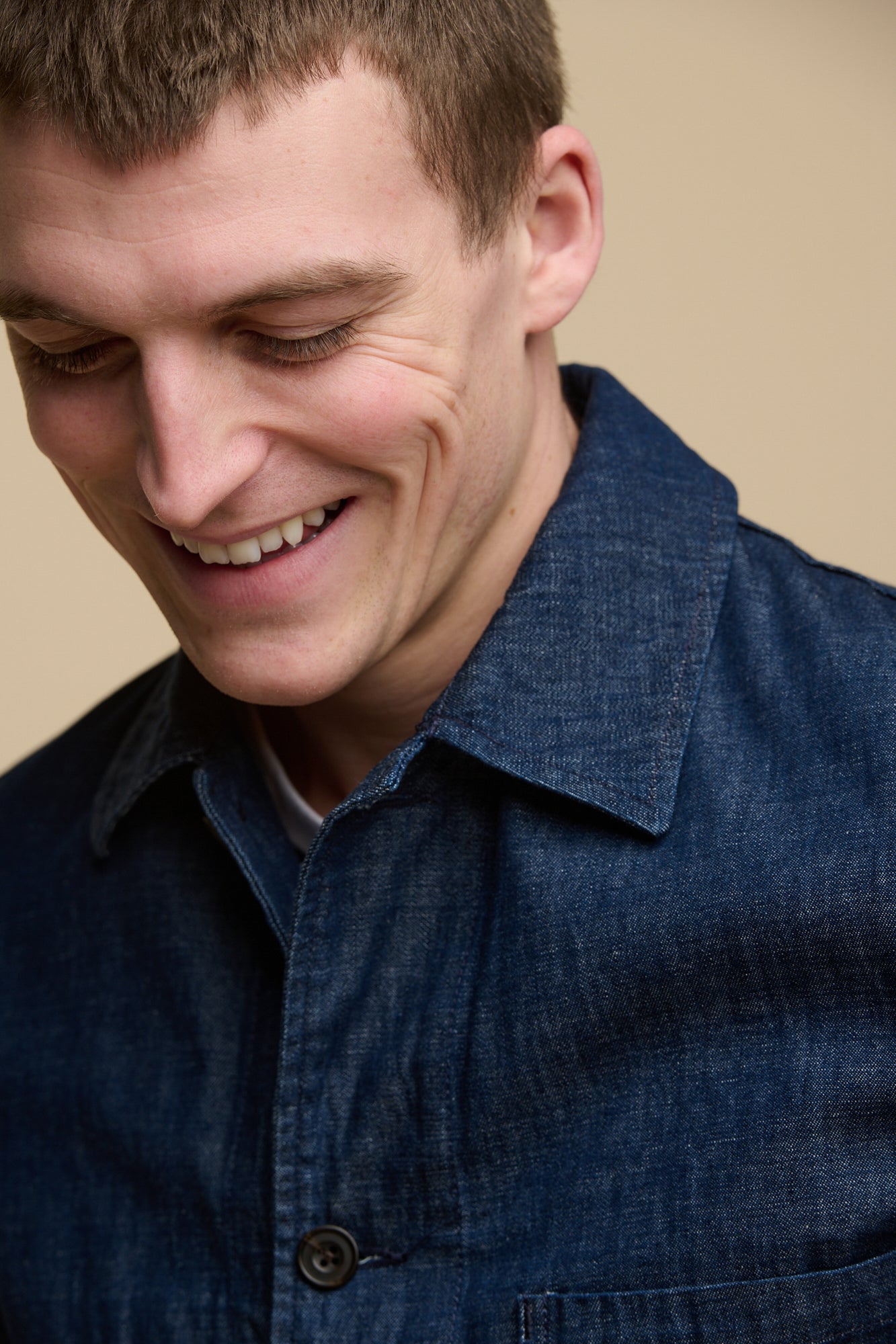 Portrait of smiley male wearing chore jacket in denim, collar and button fastening detail.