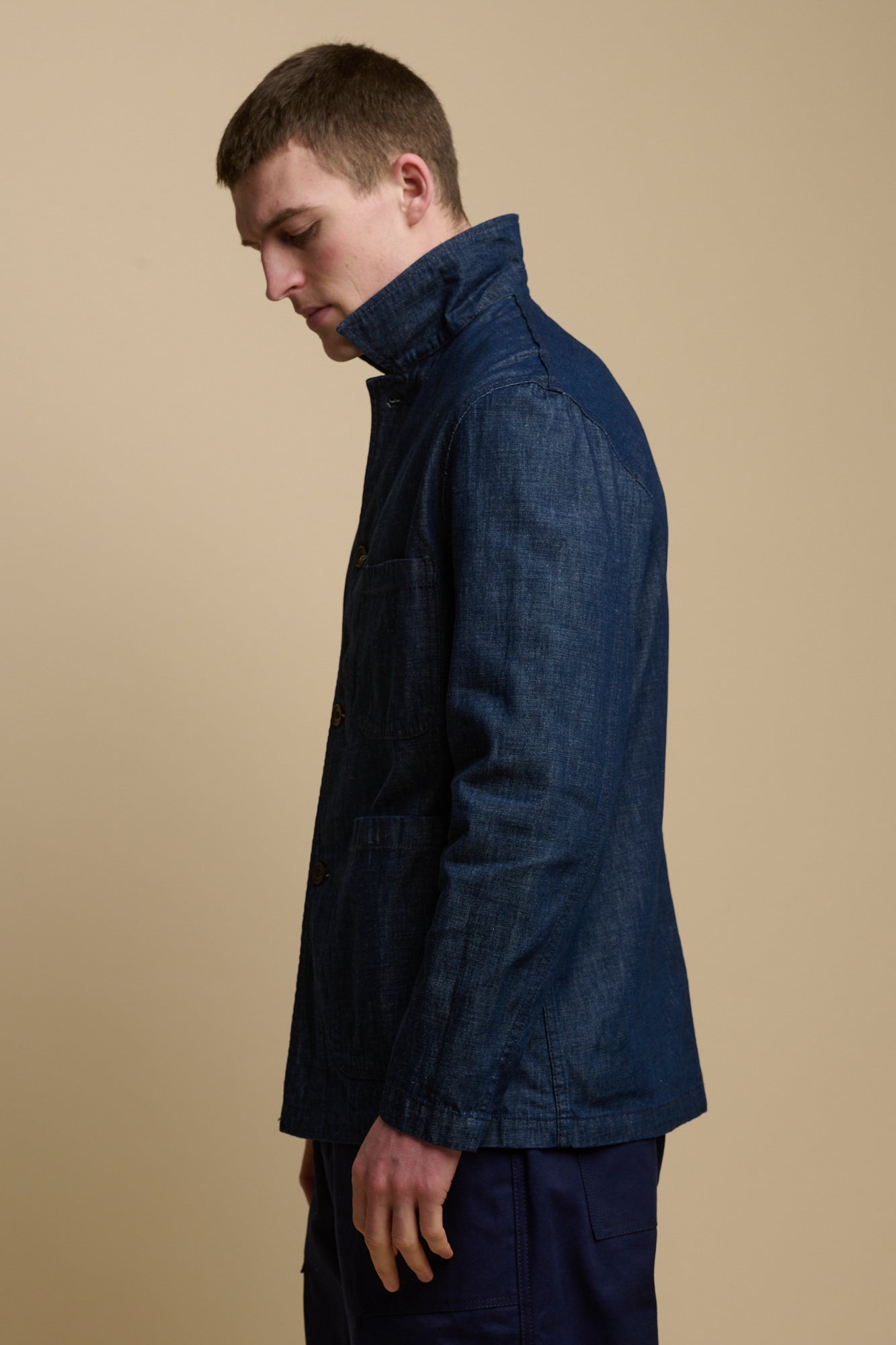 The side of male with head facing down wearing chore jacket in denim with the collar up