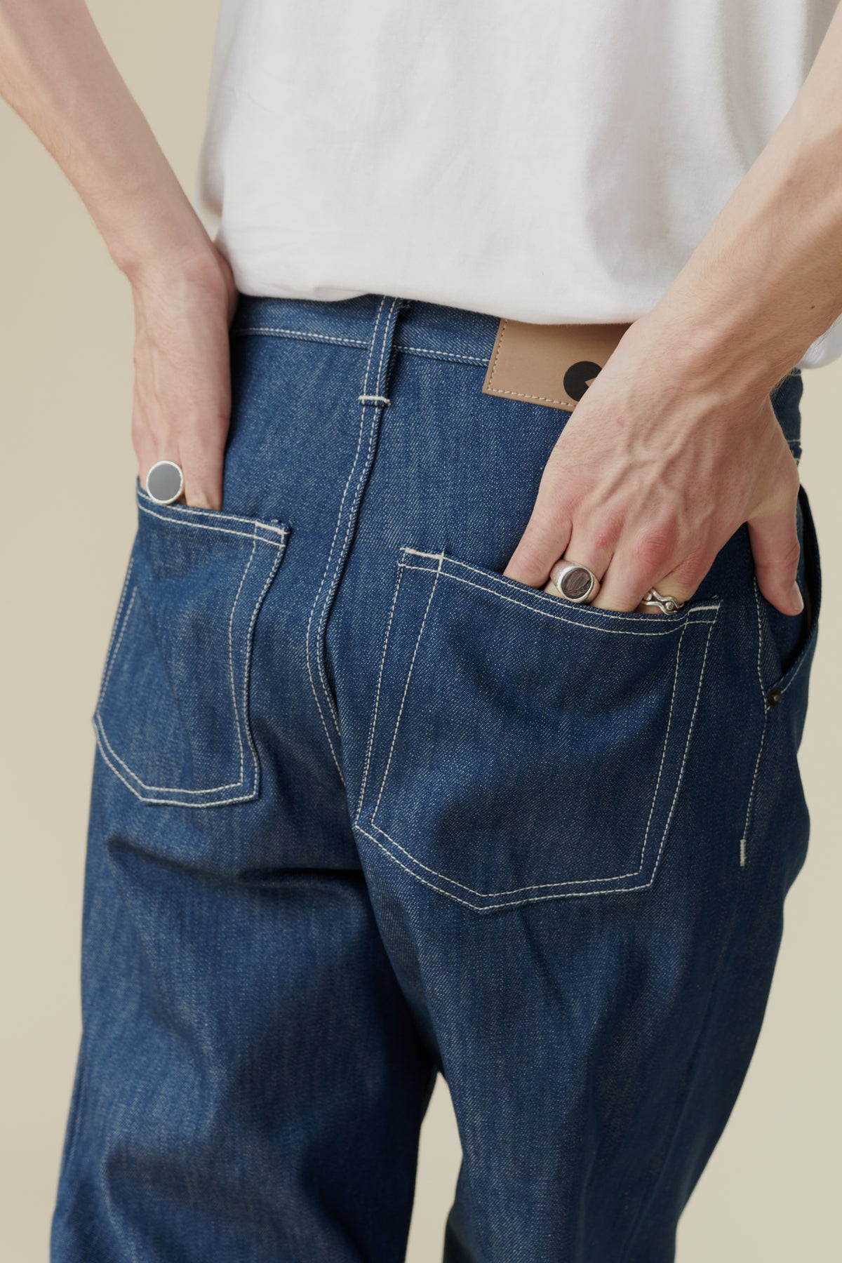 
            Image showing white male hands in back pockets of chore jean in blue, Belt loops and CC logo jean badge