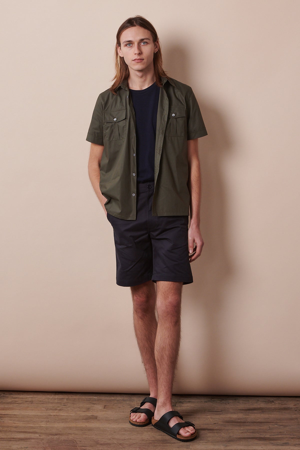 Full body image of white male wearing Classic shorts in dark navy with unbuttoned military shirt in olive