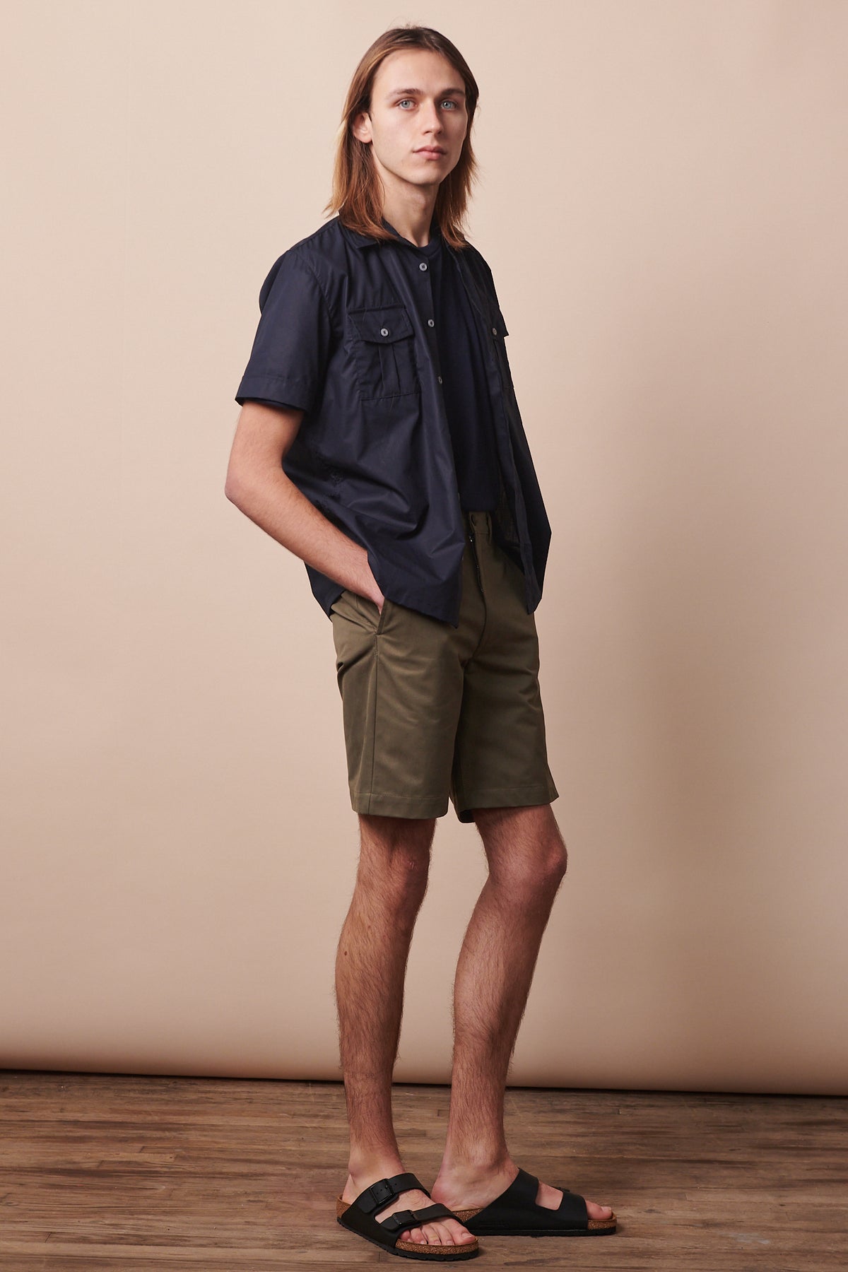 
            Full body image of the side of male wearing classic shorts in olive styled with unbuttoned military shirt in navy 