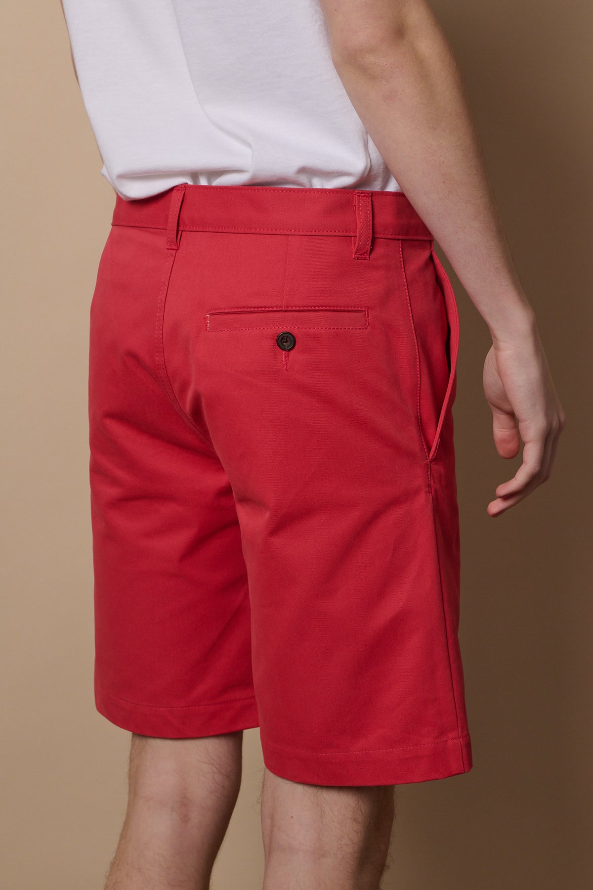 Back of salmon red shorts with back pocket and button