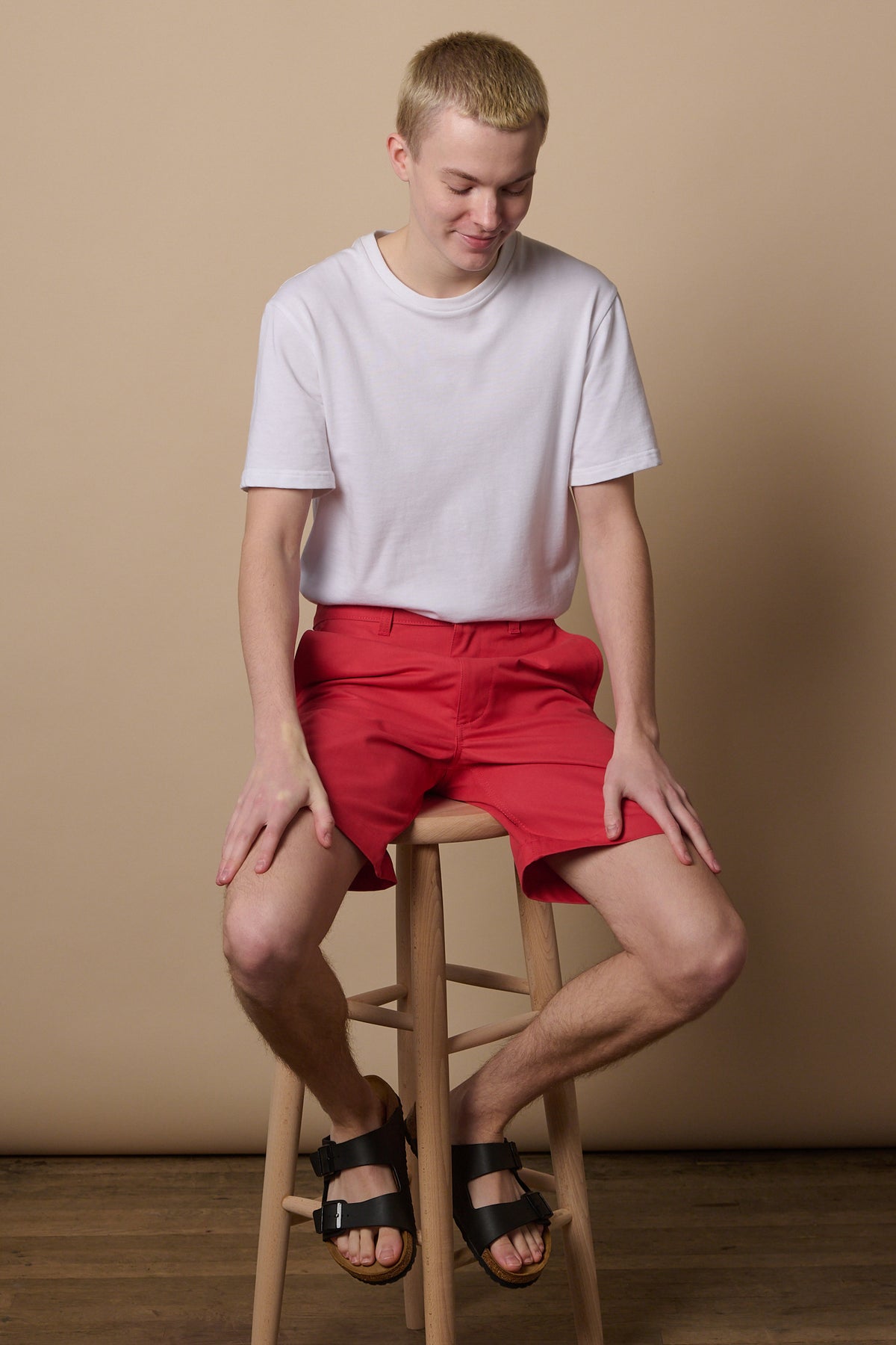 Full body image of white male wearing classic shorts in salmon blue paired with short sleeve white t shirt