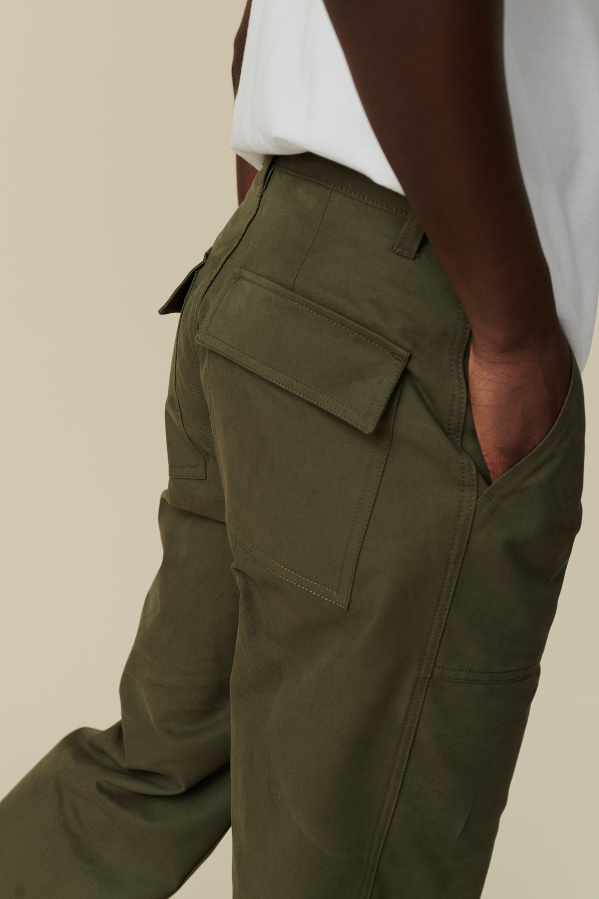 Back pocket and belt loop detail of male wearing combat trousers in olive