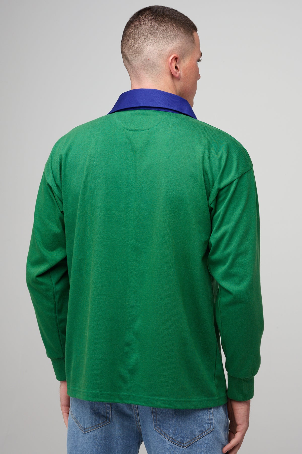 White, brunette male, facing away wearing green rugby shirt with contrast blue collar,