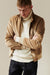 Blonde, white male wearing men's corduroy harrington jacket in stone layered over lambswool roll neck jumper in ecru