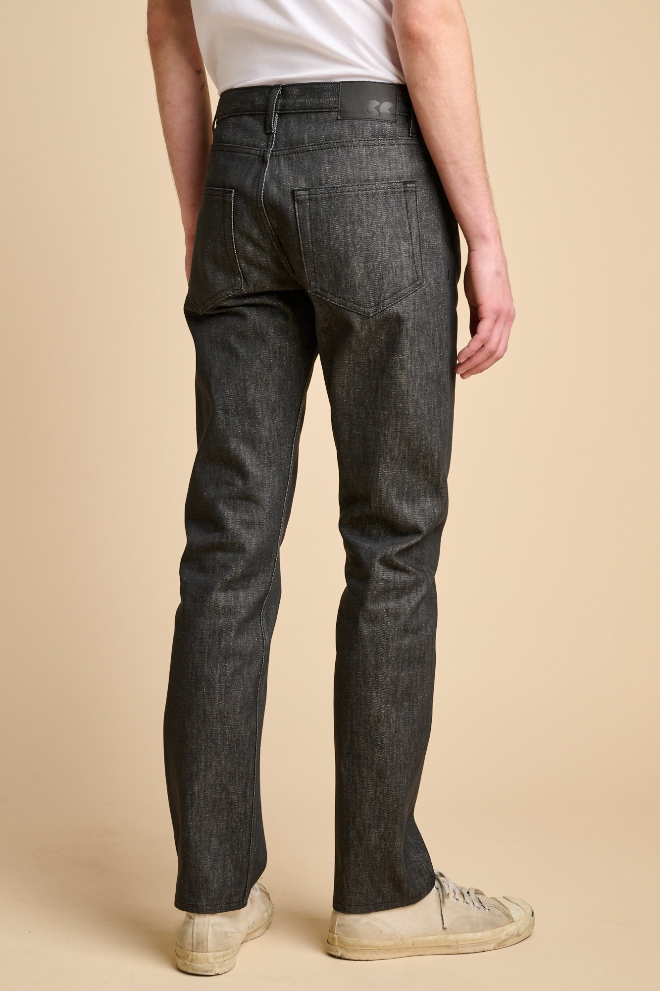 The back of man wearing slim fit jeans in black with white t shirt.