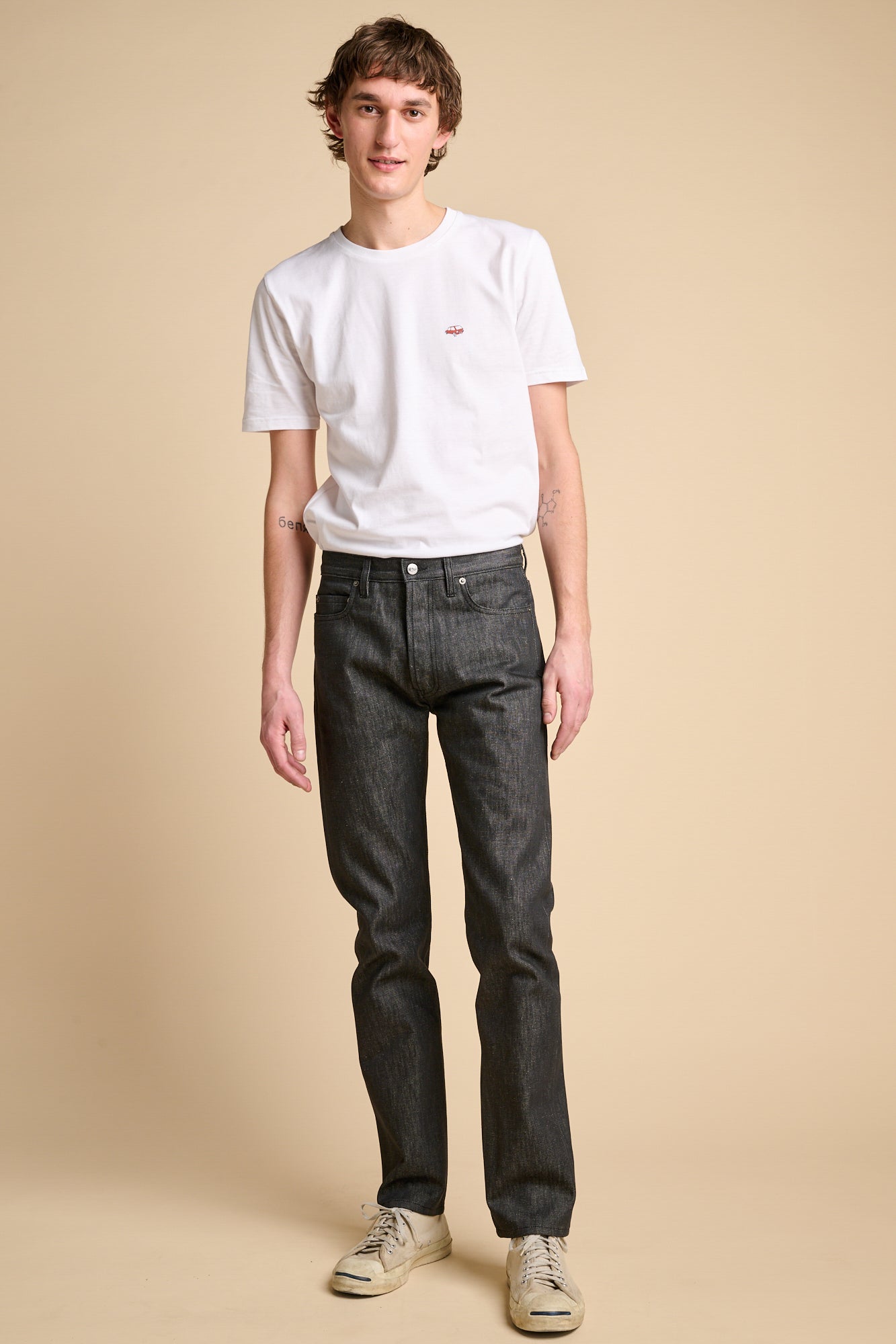 A man wearing a white crew neck t shirt paired with black slim fit jeans.