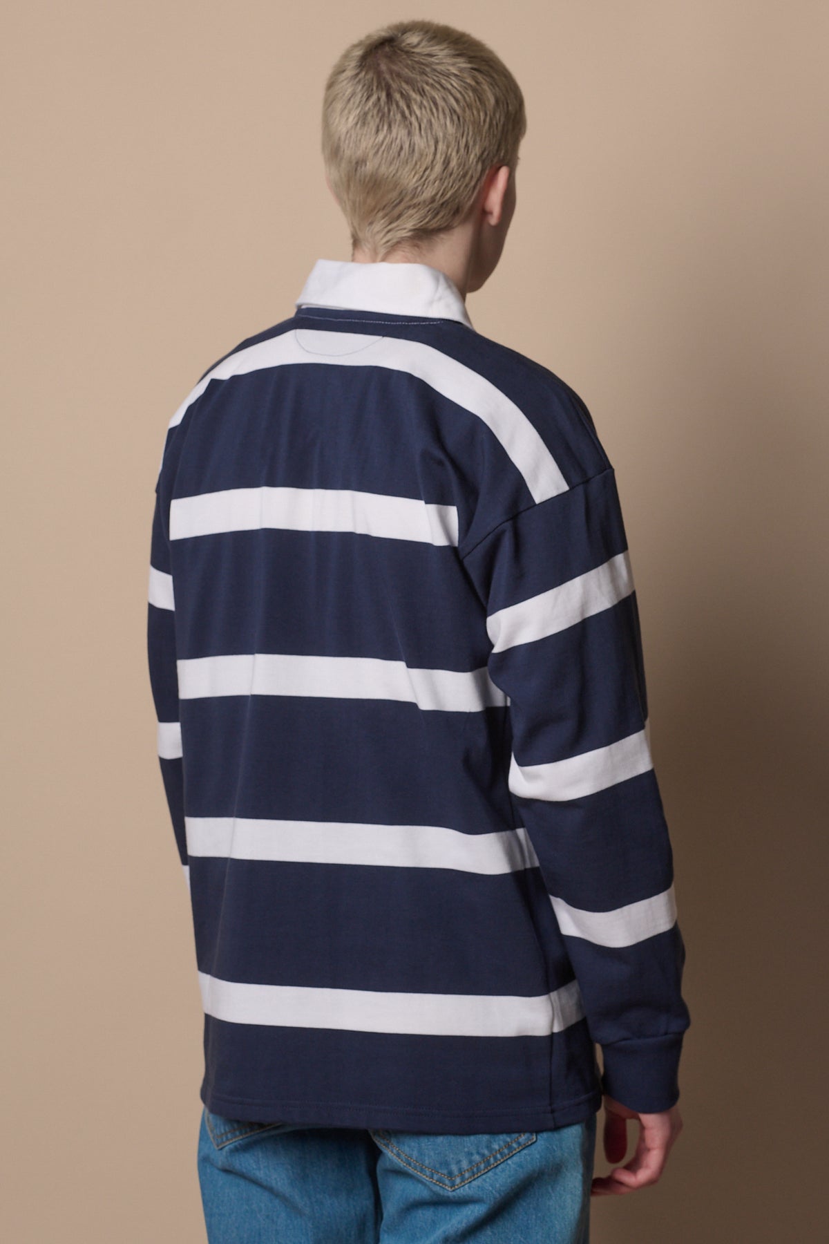 
            back of blonde male wearing stripe rugby shirt in navy white