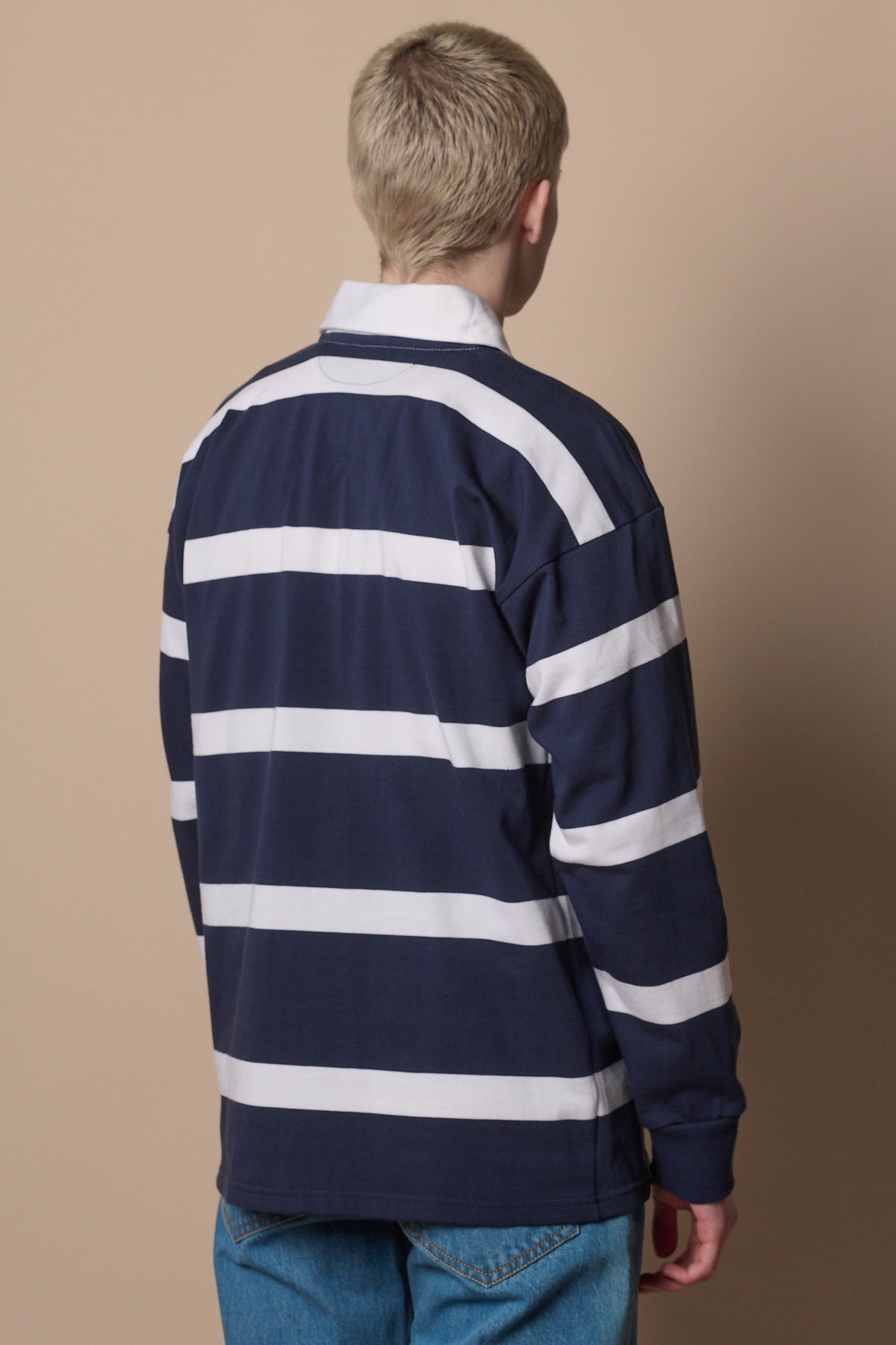 back of blonde male wearing stripe rugby shirt in navy white