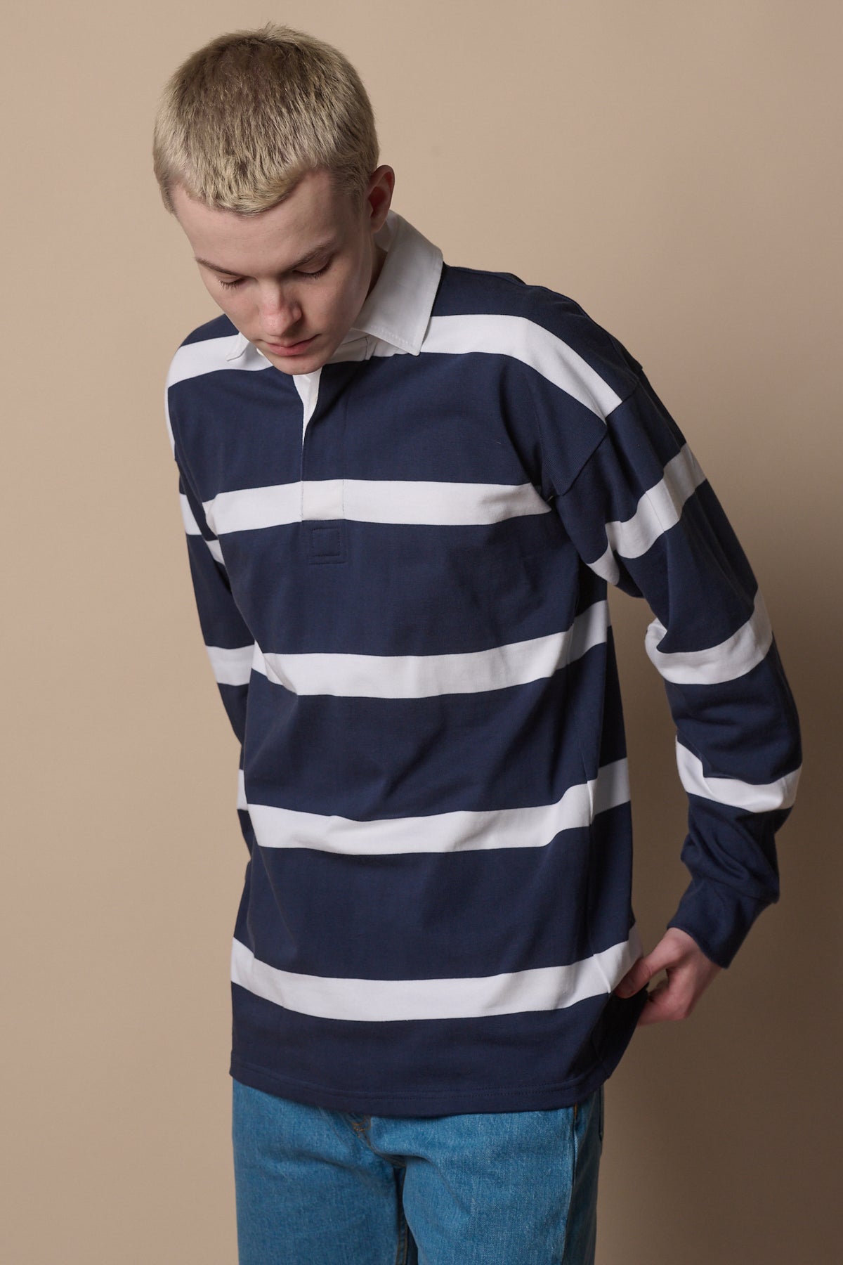 Blonde male wearing fine stripe rugby shirt in navy white