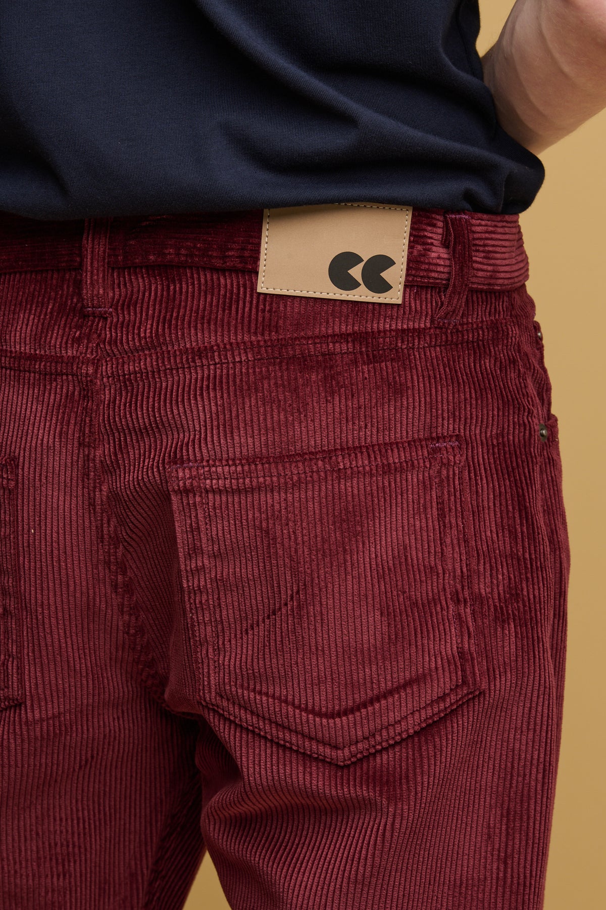 Close up of the back pockets and belt loops with CC logo jeans patch on the cord trousers in burgundy