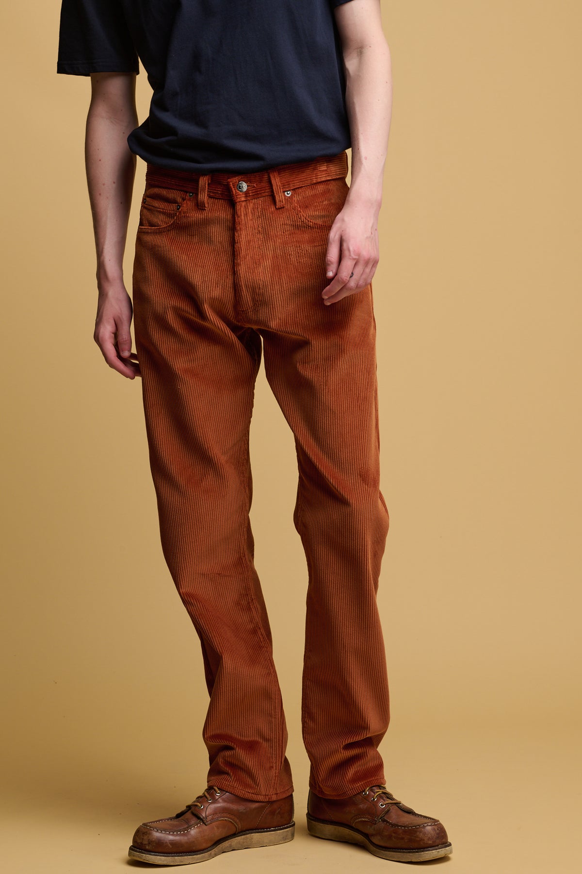 The front of male chest down wearing community clothing cord trousers in cinnamon with CC logo silver button