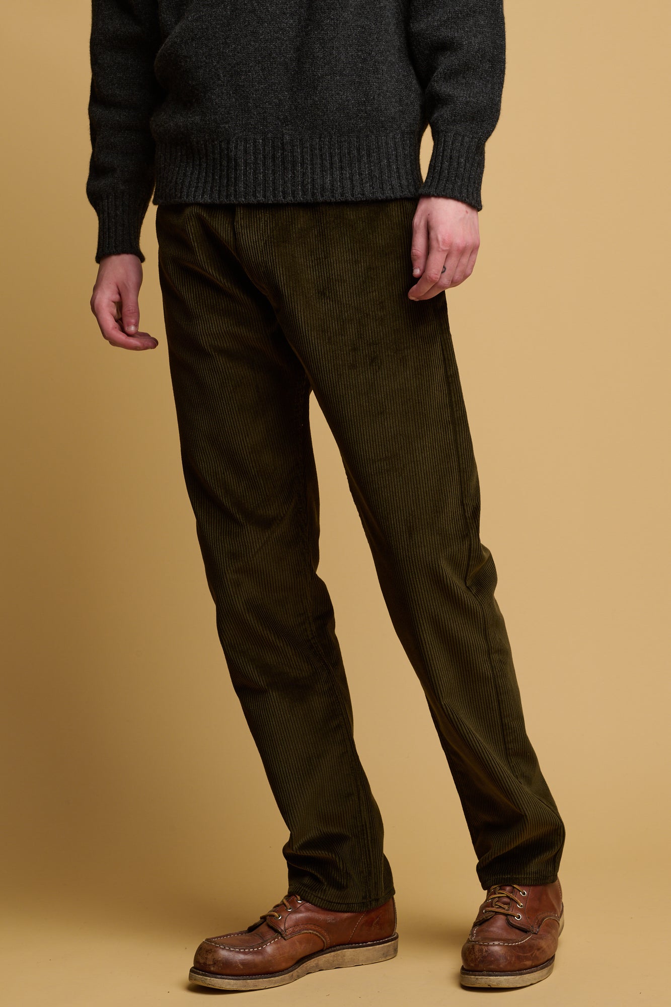 Waist down of male wearing five pocket cord trousers in olive paired with lambswool roll neck jumper