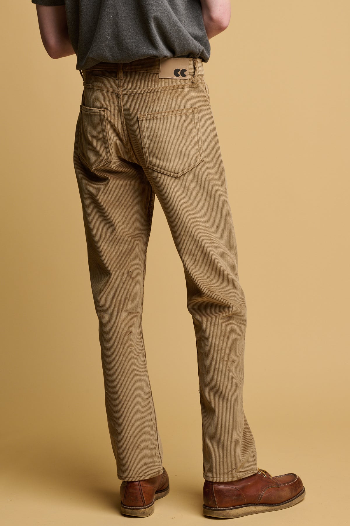 Waist down of the back of male wearing five pocket cord trousers in stone with two back pockets and belt loops with CC logo jeans patch on waistband.