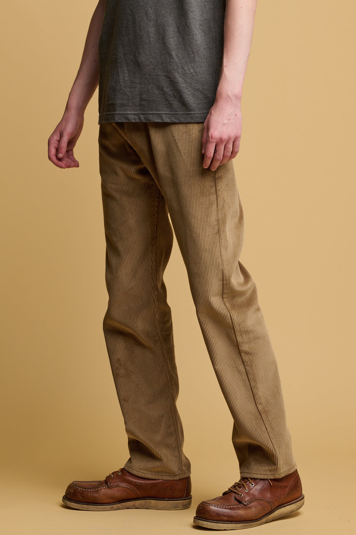 the side of male waist down wearing five pocket cord trousers in stone with brown leather shoes