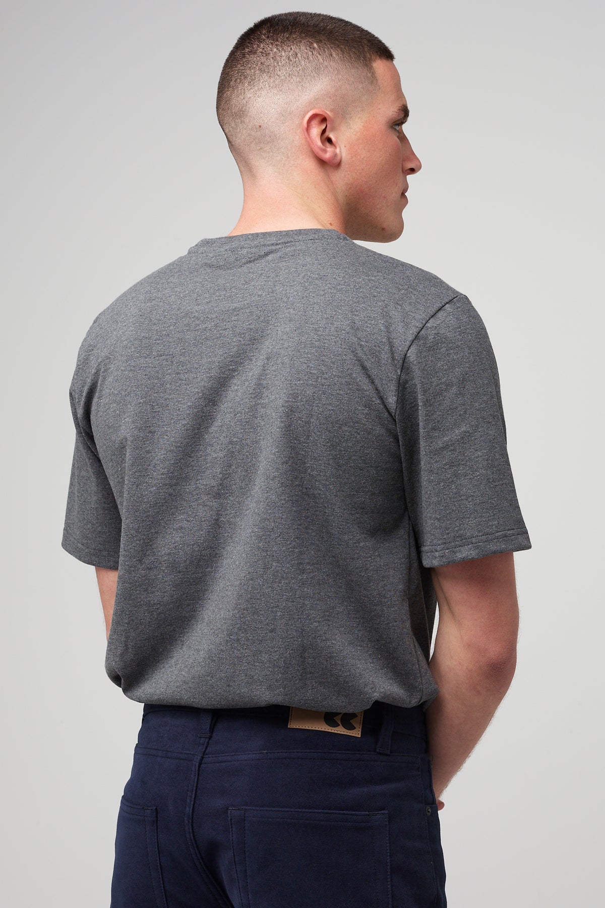 Brunette male in navy Five Pocket Moleskin Jean styled with men's charcoal short sleeve t-shirt tucked in