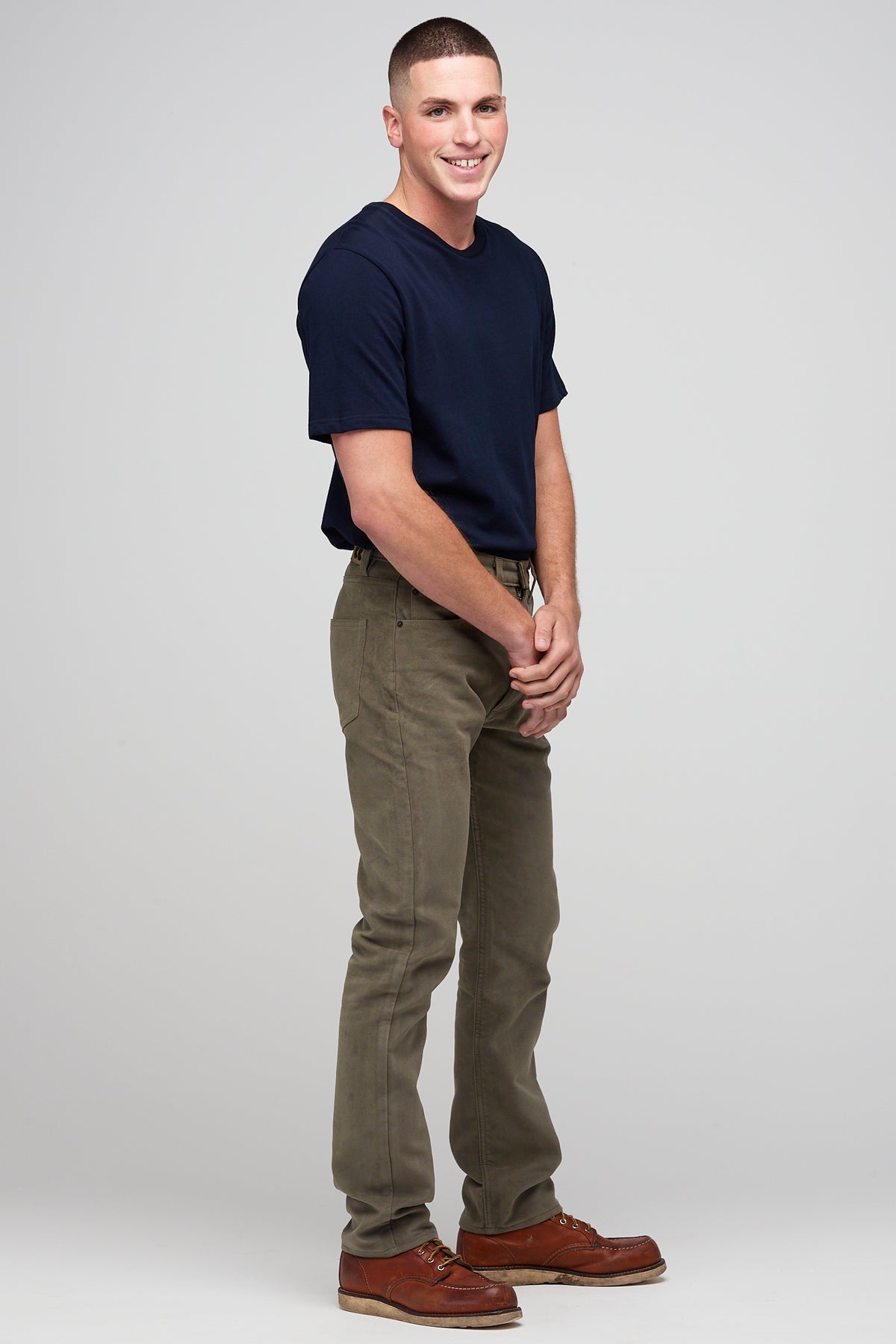 
            Brunette male in Olive Five Pocket Moleskin Jean styled with navy men&#39;s short sleeve t-shirt
