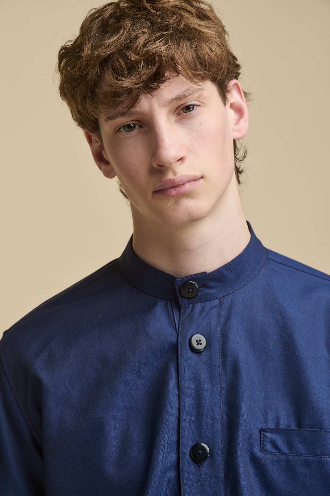 Portrait of male wearing George Lightweight Collarless Overshirt in navy with large buttons and front pocket