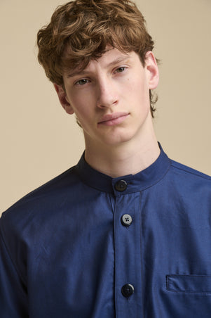 Portrait of male wearing George Lightweight Collarless Overshirt in navy with large buttons and front pocket