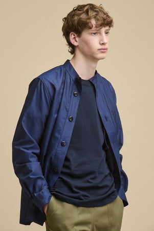 Thigh up image of male wearing George Lightweight Collarless Overshirt in navy unbuttoned over navy t shirt