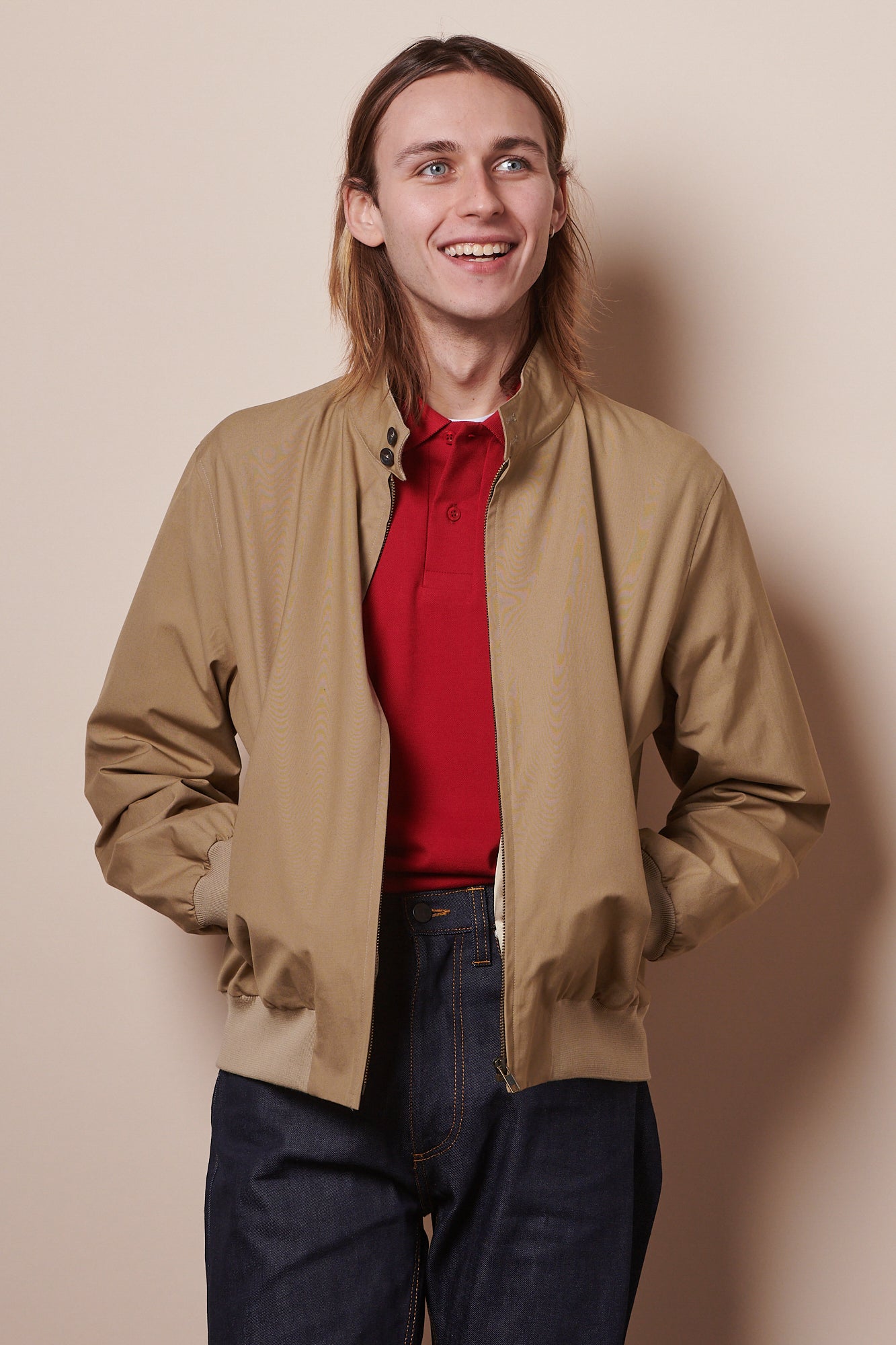 Smiley male wearing Harrington jacket unzipped with hands in pockets. 