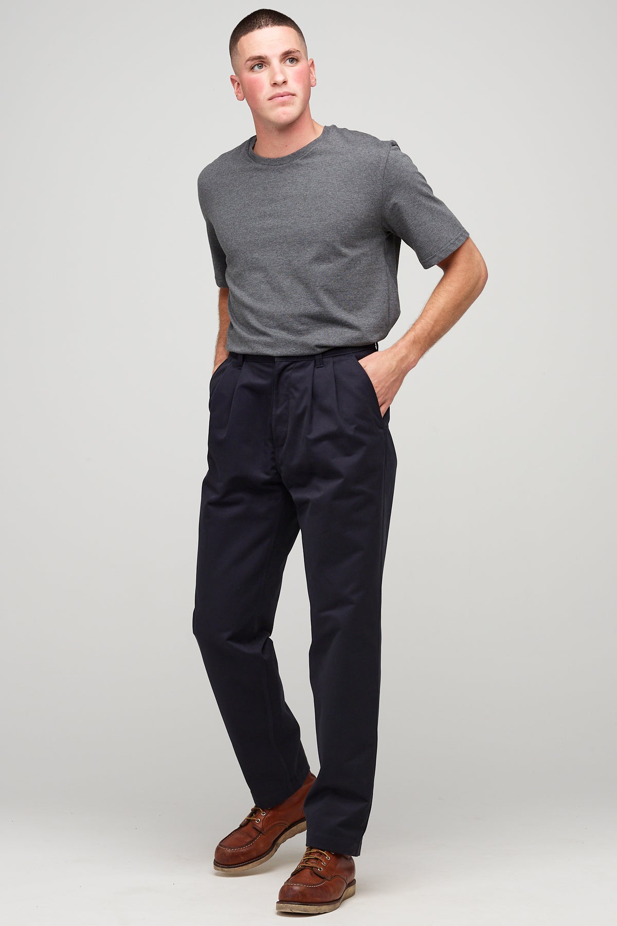 white male, brunette wearing heavyweight pleated chino in navy styled with charcoal short sleeve t shirt