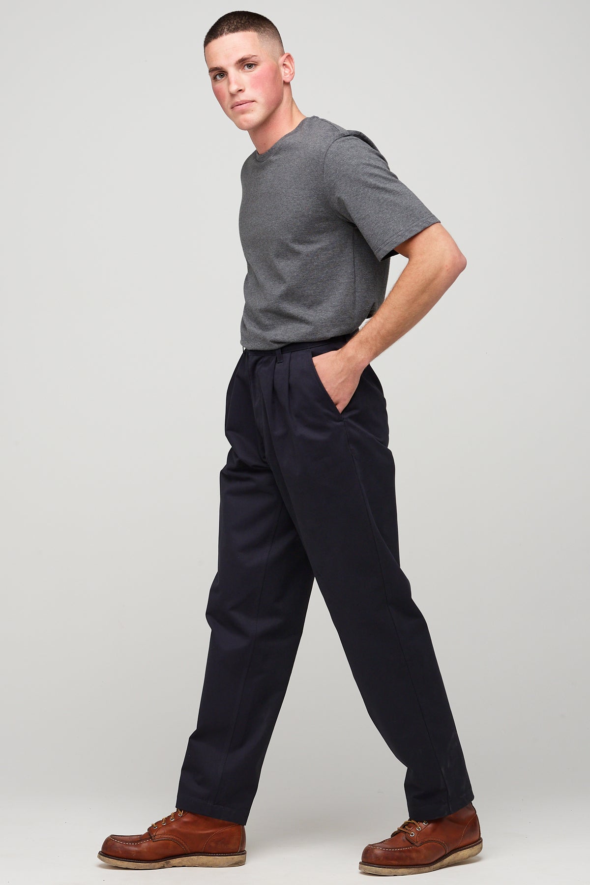 white male, brunette wearing heavyweight pleated chino in navy styled with charcoal short sleeve t-shirt