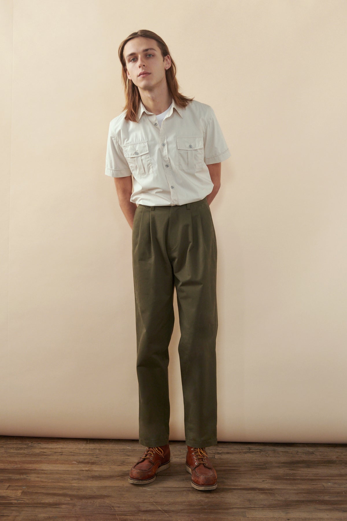 
            Male with shoulder length brown hair wearing Men&#39;s Heavyweight Pleated Chino in olive paired with pale military shirt