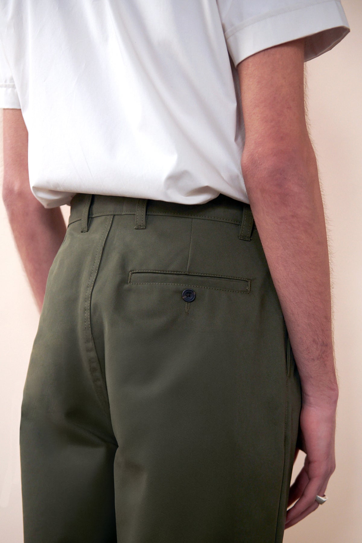 
            Close up of back of men&#39;s heavyweight pleated chino in olive. image shows back pocket with button and belt loops on waistband.