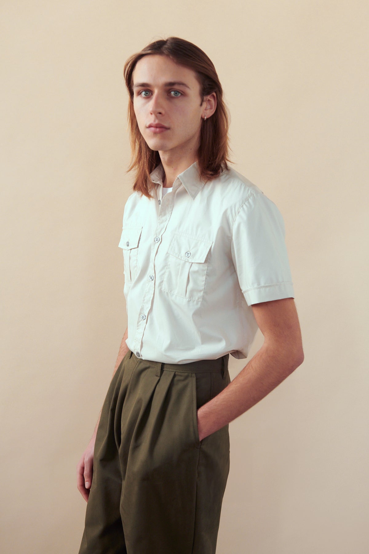 Portrait of male wearing Men's Heavyweight Pleated Chino in olive with hand in one of front pockets.