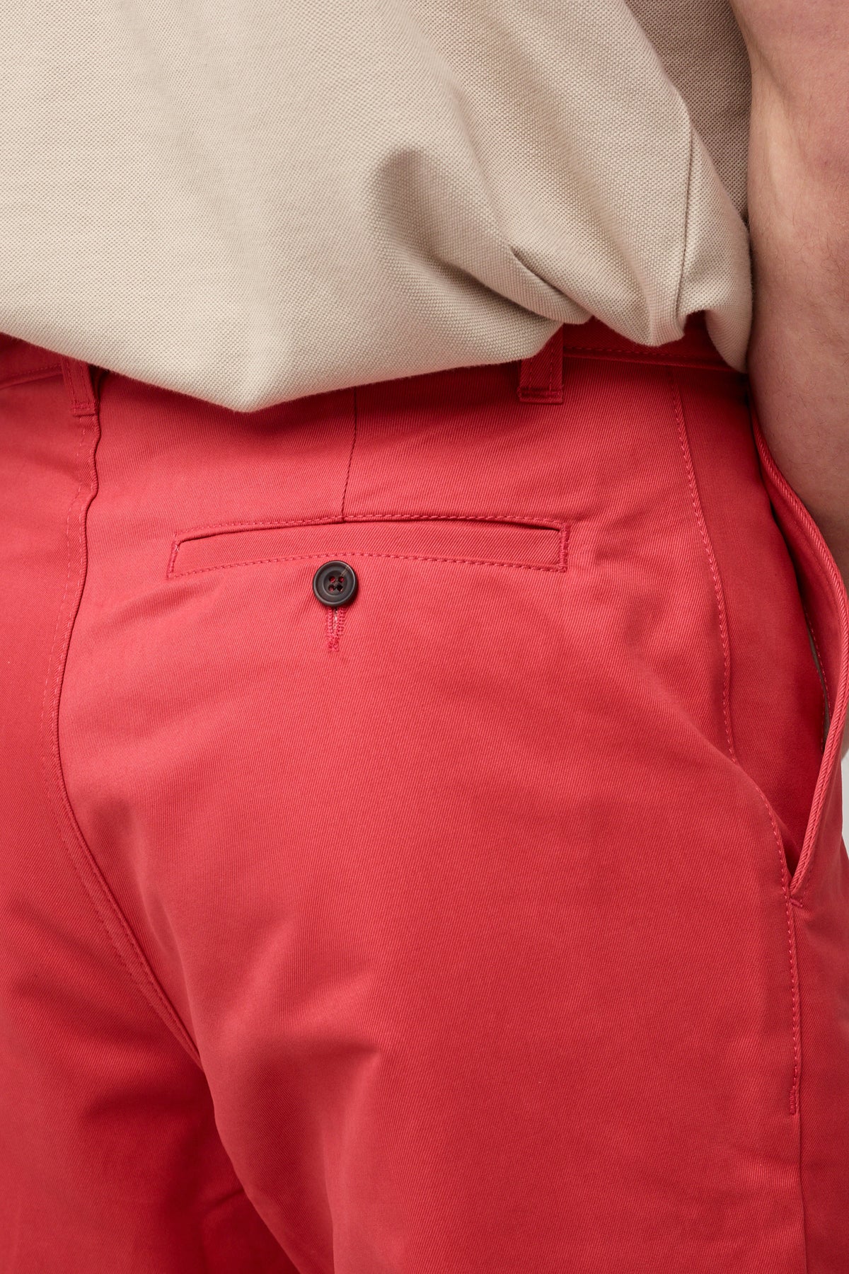 
            White, brunette male in salmon red, heavyweight relaxed chino styled with stone short sleeve polo shirt tucked in back pocket, button detail