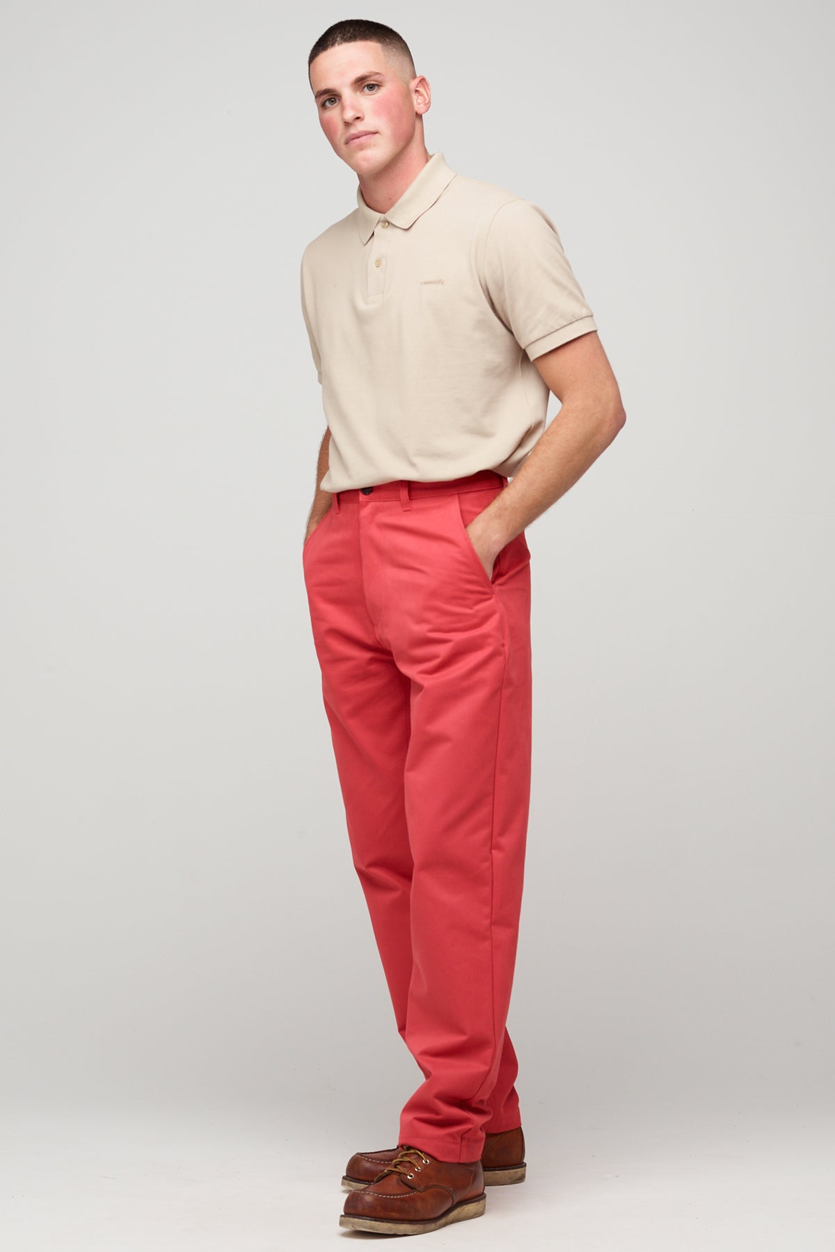 White, brunette male in salmon red, heavyweight relaxed chino styled with stone short sleeve polo shirt