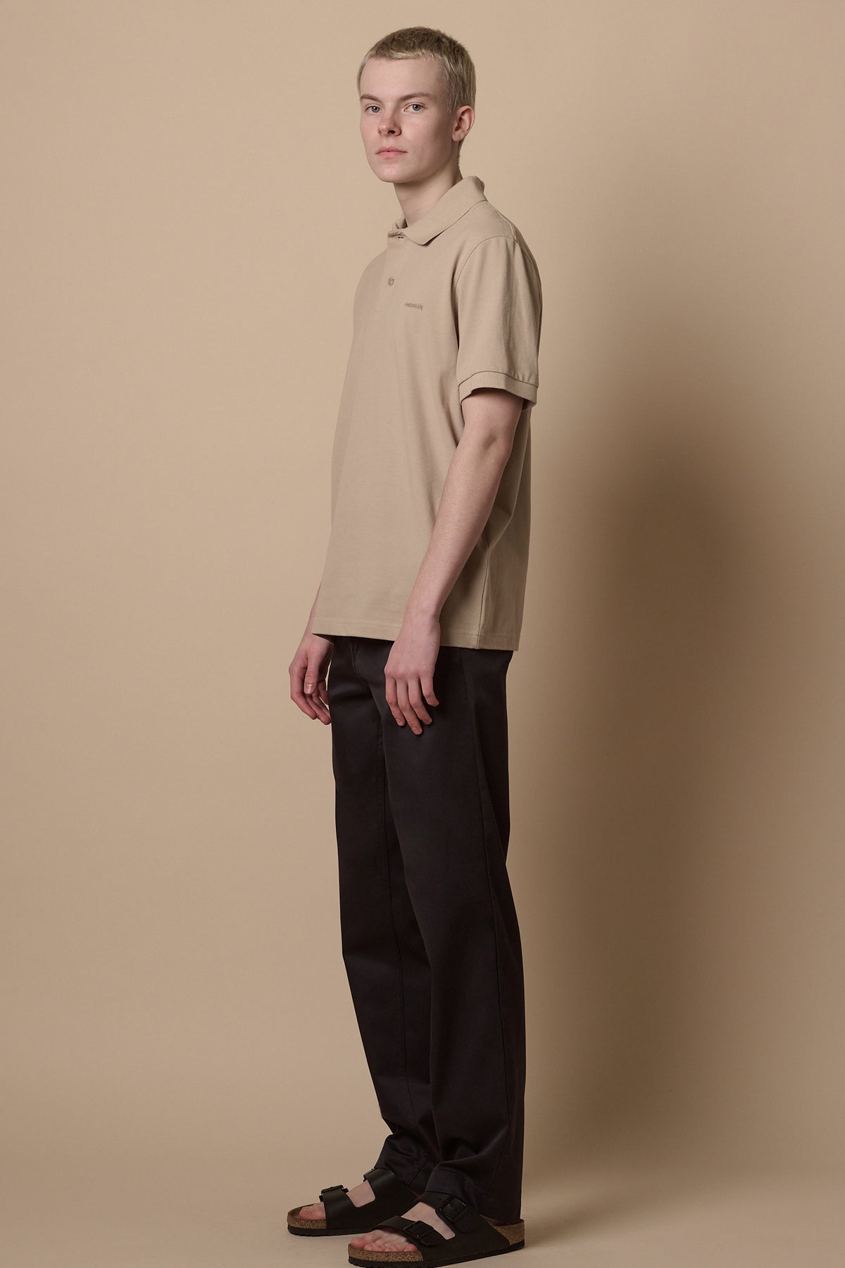 
            Full body image of male standing at an angle wearing heavyweight slim chino in navy paired with short sleeve polo shirt