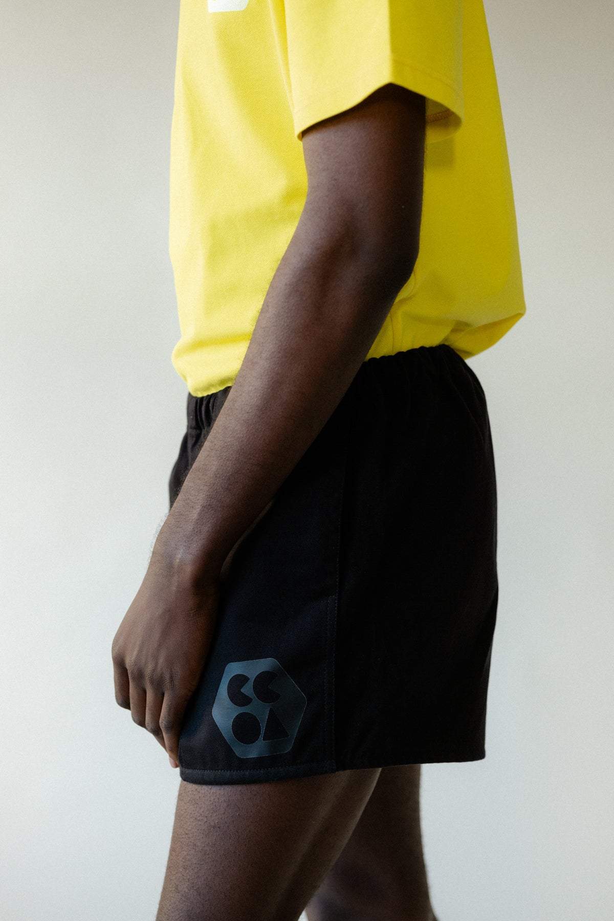 
            Image showing the side of black male chest to knee wearing men&#39;s heavyweight sports short plastic free in black with CCOA logo