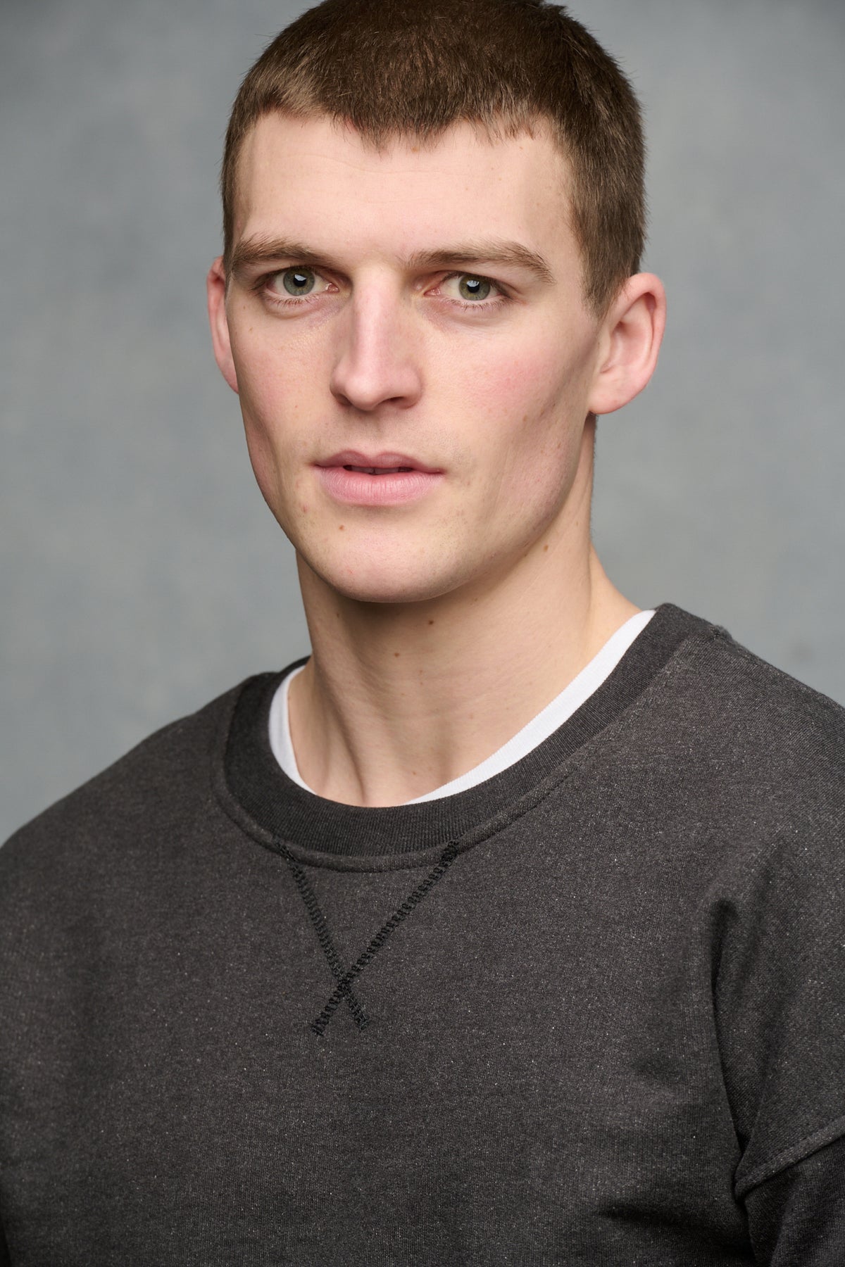 Portrait of male wearing drop shoulder heritage sweatshirt in charcoal, rib neckline detail worn over crew neck in white