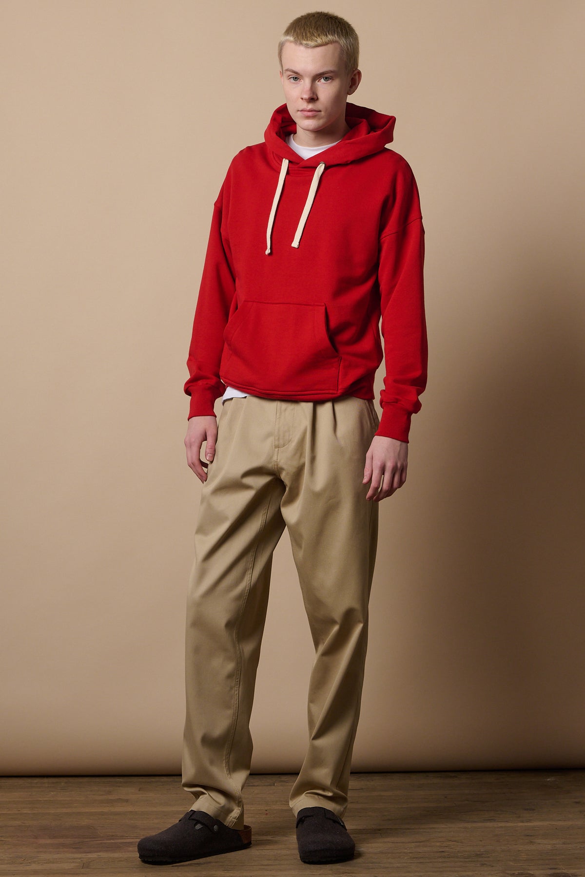 Full body image of white male wearing hooded sweatshirt in crimson