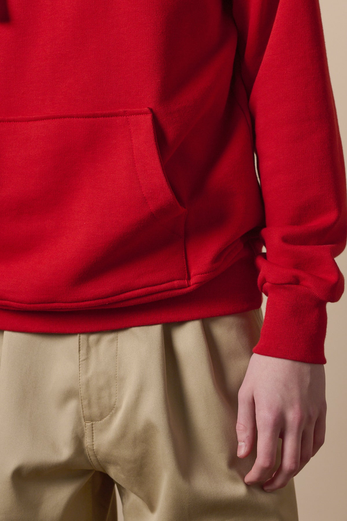 Close up image of the front pocket on the hooded sweatshirt in crimson