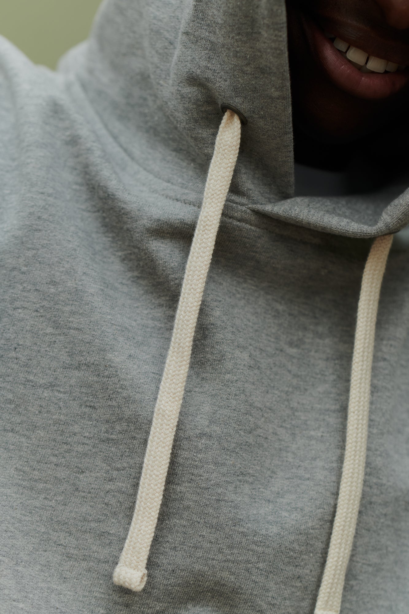 Male wearing hooded sweatshirt in grey front drawstring hood detail