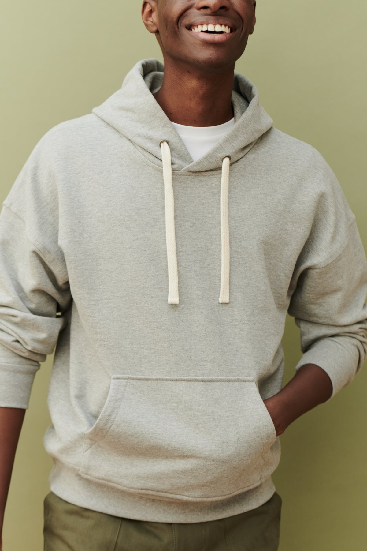 
            Male wearing hooded sweatshirt in grey front pocket detail