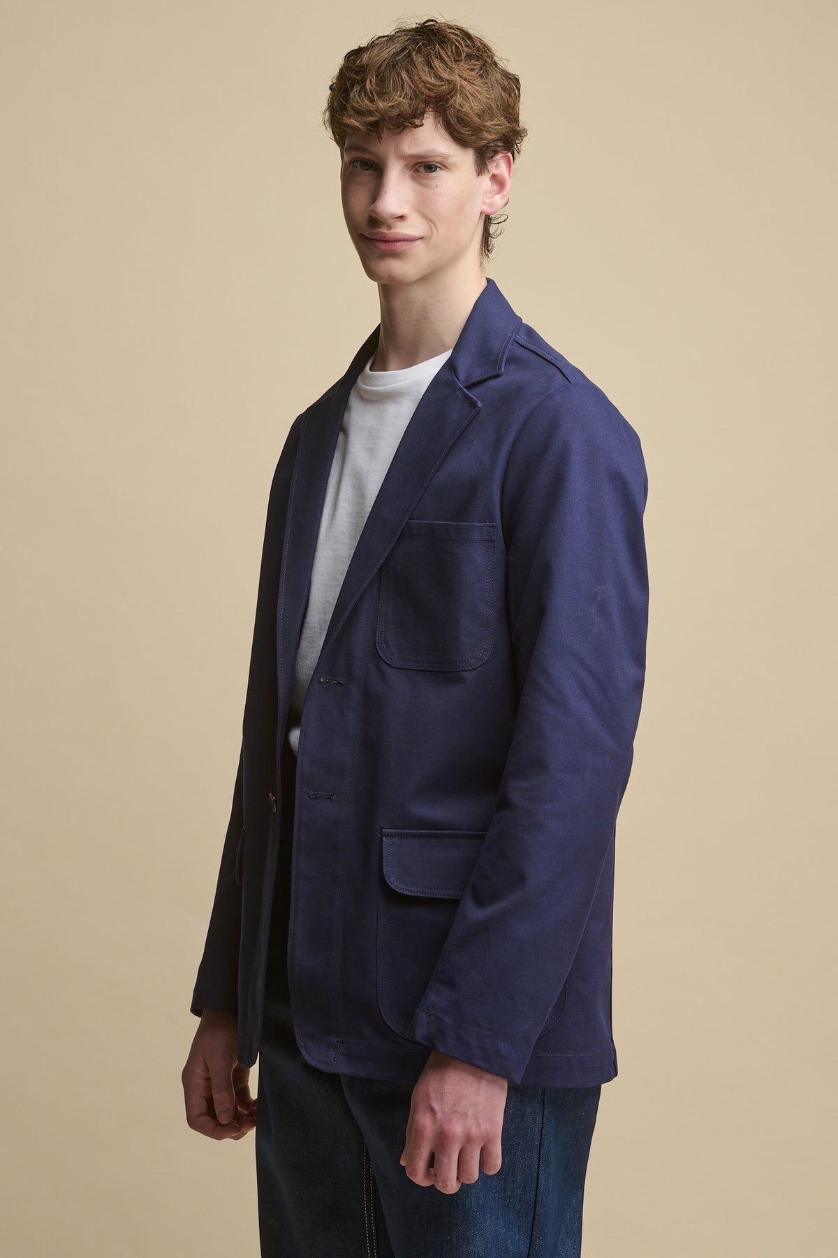Thigh up image of white male wearing Men's James Single Breasted Blazer in Navy over white t shirt. Jacket has two front pockets with flaps and one chest pocket