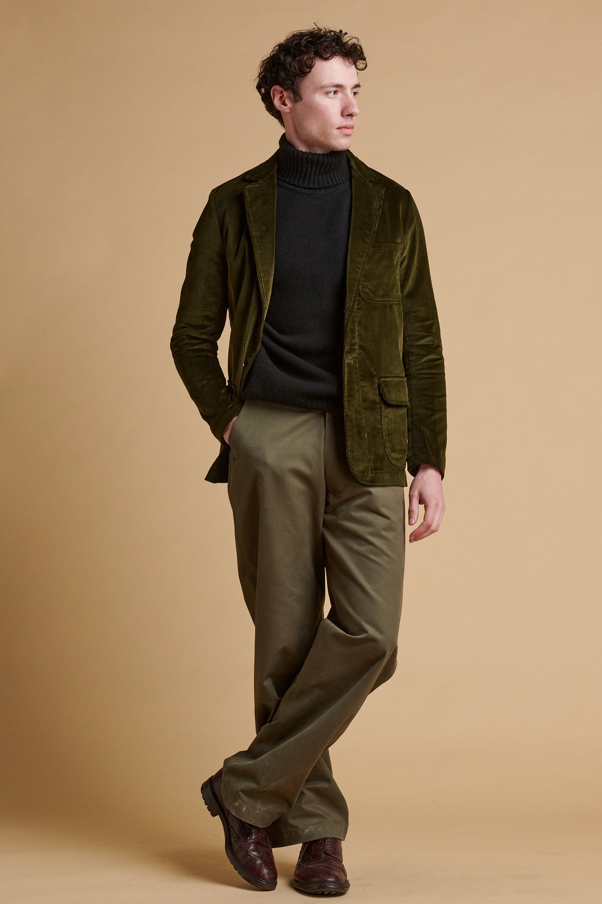 Male wearing James single breasted corduroy blazer in olive over navy lambswool roll neck.