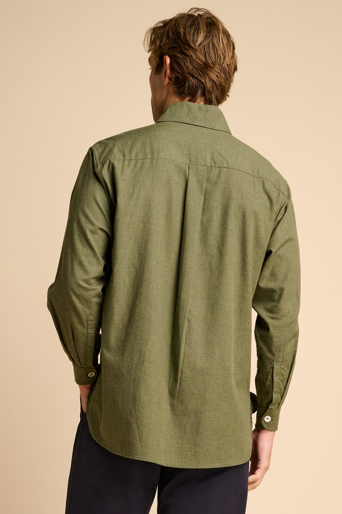 Man wearing green shirt against beige background. 