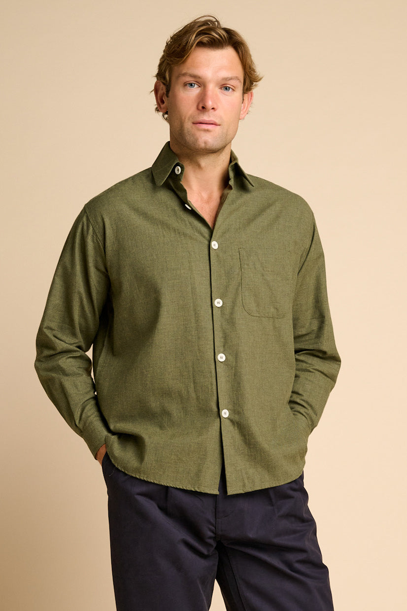 Man wearing green shirt against beige background. 