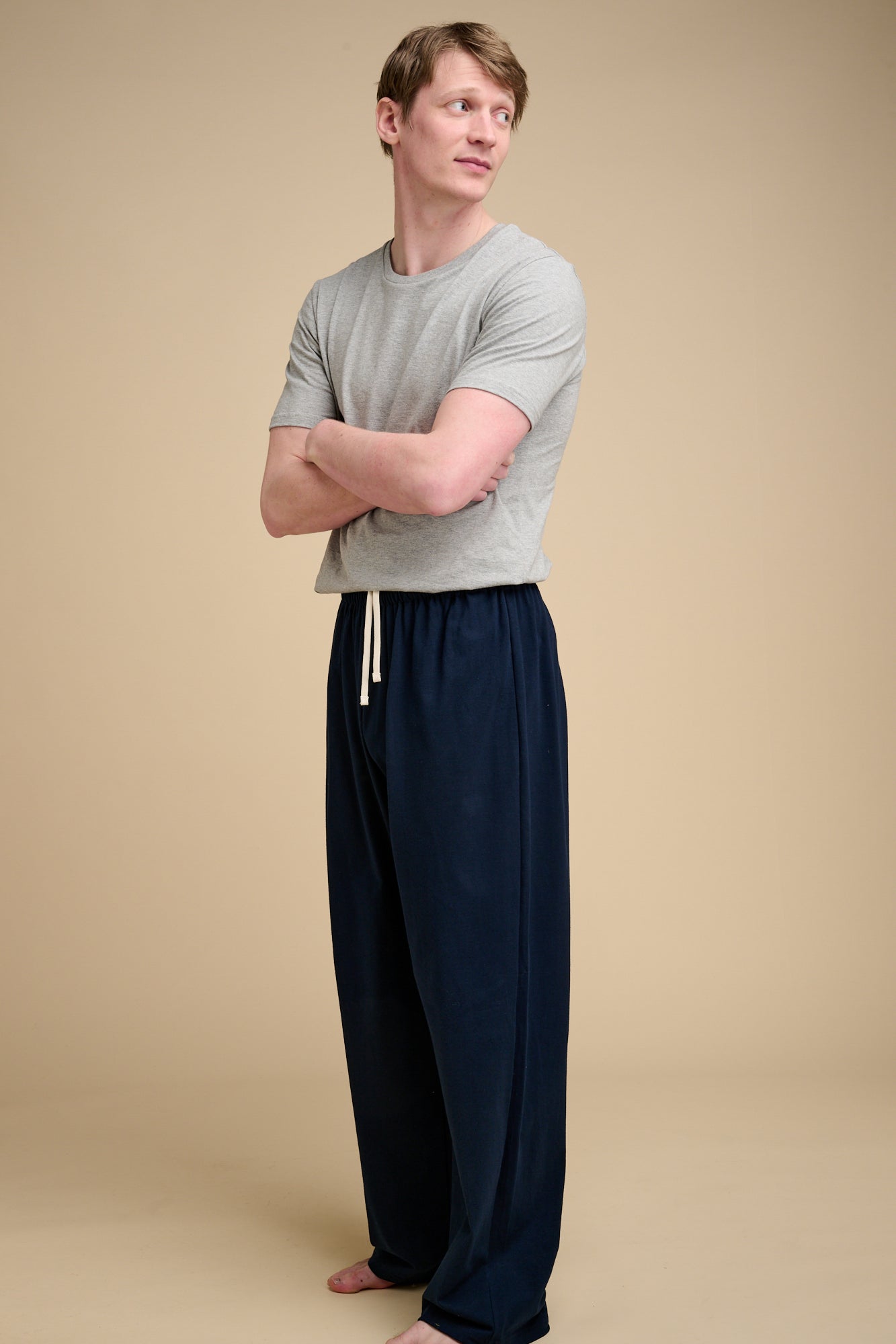 Man wearing navy pyjama bottom with grey t shirt.