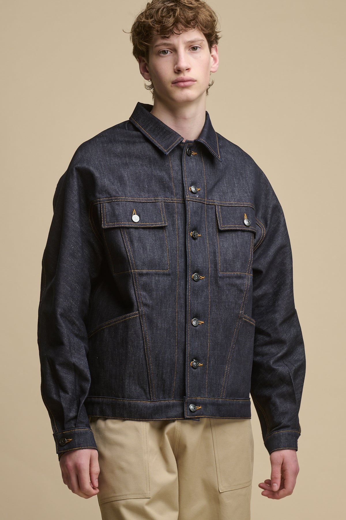 Thigh up image of male wearing joe denim jacket in indigo fastened with all buttons