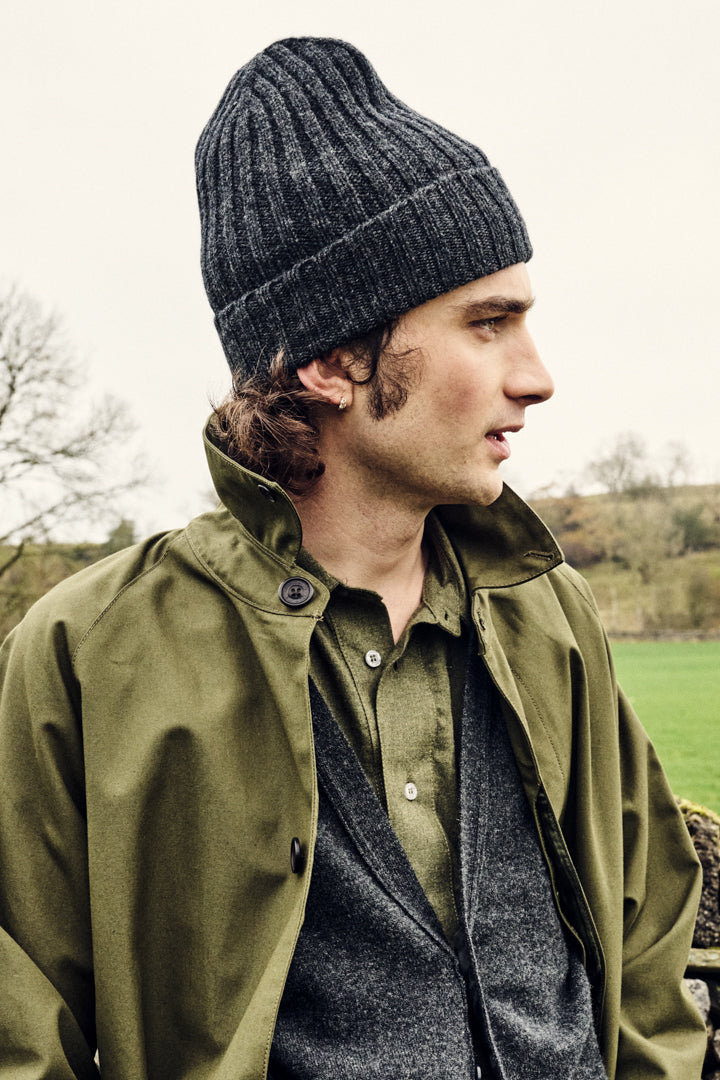 Man wearing a green jacket and gray beanie outdoors